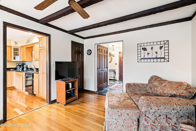 living room featuring sink, light hardwood / wood-style floors, ceiling fan, and beam ceiling