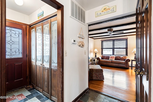 foyer featuring a baseboard radiator, dark hardwood / wood-style floors, ceiling fan, and beam ceiling