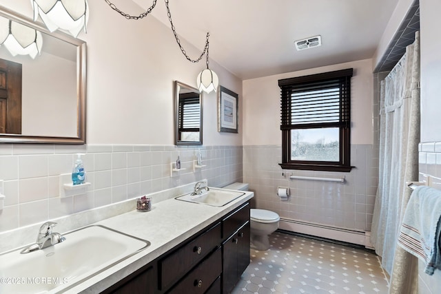 bathroom with vanity, tile walls, toilet, and a baseboard radiator