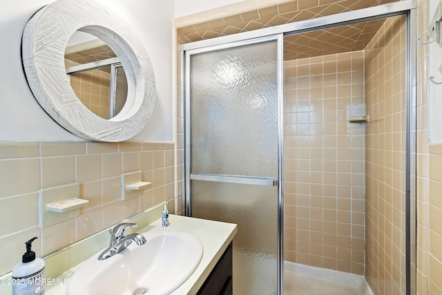 bathroom featuring tile walls, vanity, and a shower with shower door