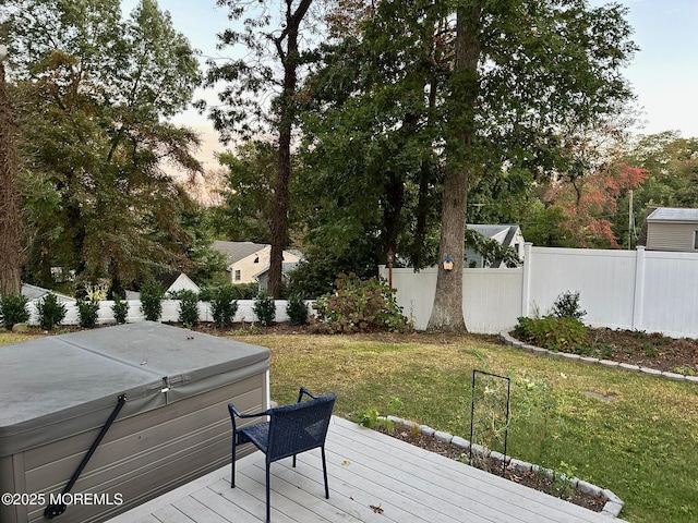 deck at dusk featuring a hot tub and a lawn