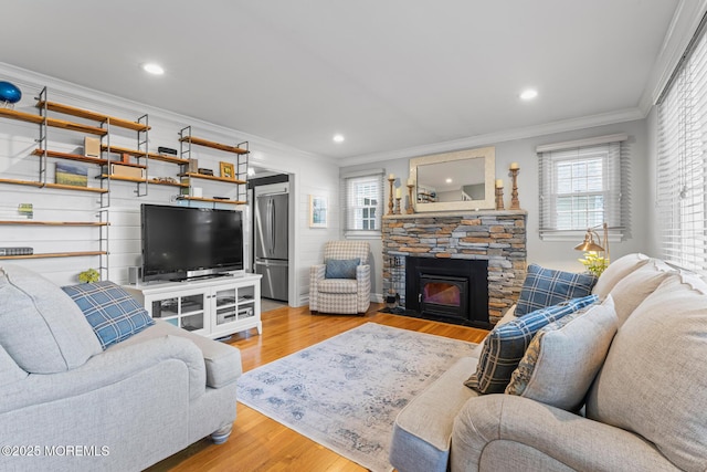 living room featuring ornamental molding, a stone fireplace, and light hardwood / wood-style floors