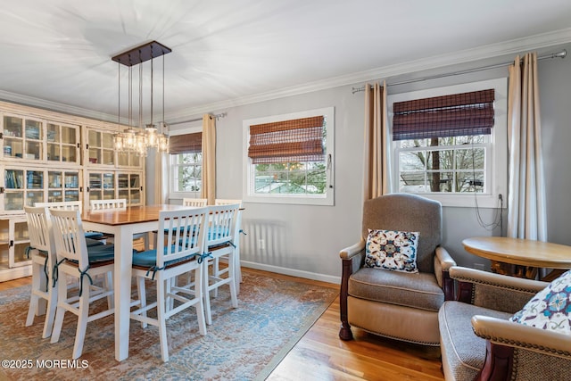 dining area featuring ornamental molding, a notable chandelier, and light wood-type flooring