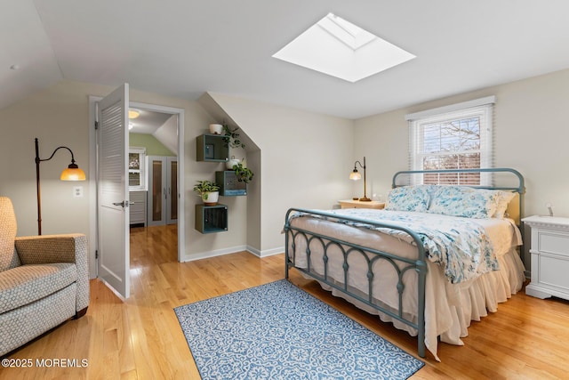 bedroom featuring light hardwood / wood-style flooring and vaulted ceiling with skylight