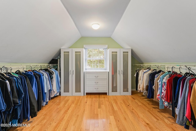 walk in closet featuring vaulted ceiling and light hardwood / wood-style floors