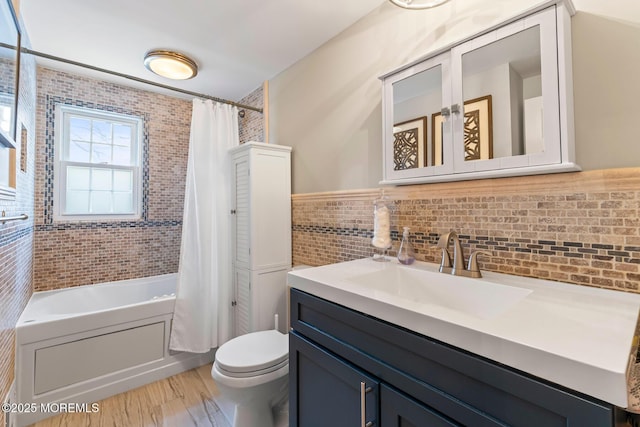 full bathroom with shower / tub combo with curtain, toilet, tile walls, vanity, and hardwood / wood-style floors