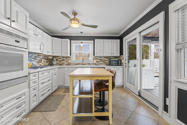 kitchen featuring light tile patterned floors, ornamental molding, stainless steel appliances, and white cabinets