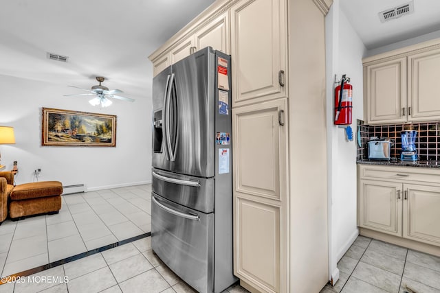 kitchen with stainless steel refrigerator with ice dispenser, light tile patterned flooring, baseboard heating, and cream cabinetry