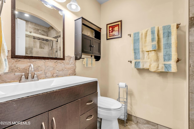 bathroom with vanity, toilet, a shower with shower door, and backsplash