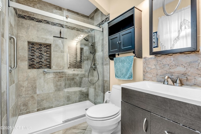 bathroom featuring a shower with door, toilet, vanity, and decorative backsplash