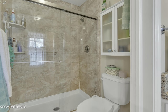 bathroom featuring a shower with door and toilet