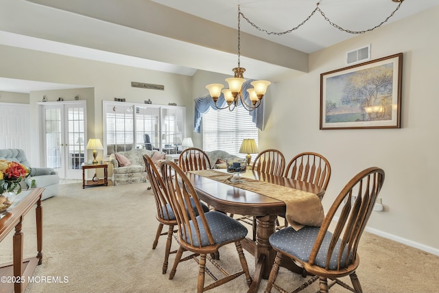 carpeted dining room with an inviting chandelier and french doors