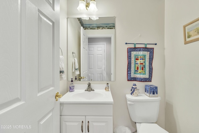 bathroom featuring vanity, toilet, and an inviting chandelier