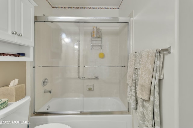 bathroom with toilet and bath / shower combo with glass door