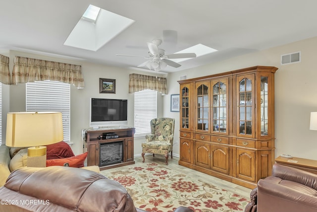 living room featuring ceiling fan and a skylight