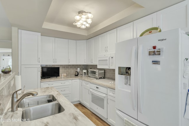 kitchen with sink, white cabinetry, a raised ceiling, white appliances, and backsplash