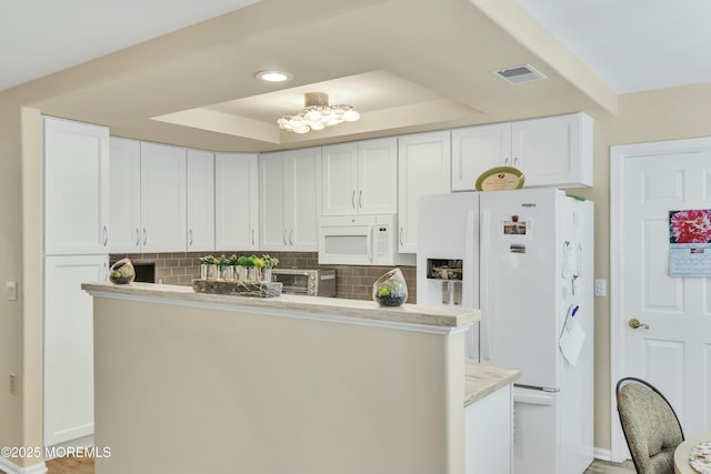 kitchen with white cabinetry, white appliances, a raised ceiling, and backsplash