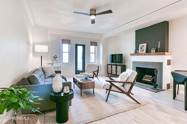 living room with a textured ceiling, ceiling fan, and light hardwood / wood-style floors