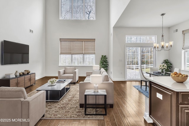 living room featuring hardwood / wood-style floors, a notable chandelier, and a towering ceiling