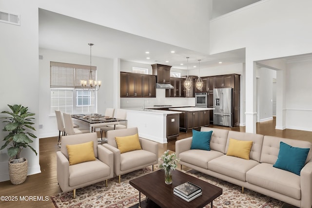 living room featuring a high ceiling, dark hardwood / wood-style floors, and an inviting chandelier