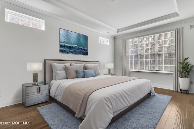 bedroom with crown molding, a tray ceiling, and dark wood-type flooring