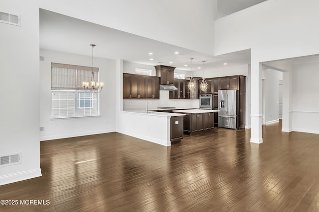 kitchen featuring dark brown cabinetry, stainless steel appliances, dark hardwood / wood-style floors, and hanging light fixtures