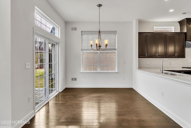 unfurnished dining area with dark hardwood / wood-style floors, sink, and a notable chandelier