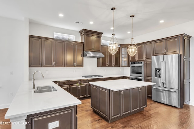 kitchen featuring hanging light fixtures, a center island, appliances with stainless steel finishes, and sink