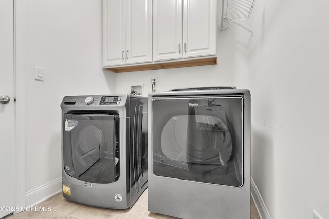 clothes washing area featuring cabinets, washing machine and clothes dryer, and light tile patterned flooring