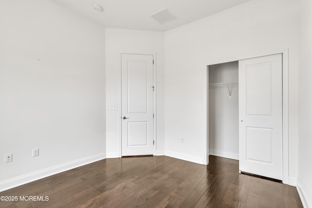 unfurnished bedroom with dark hardwood / wood-style flooring and a closet