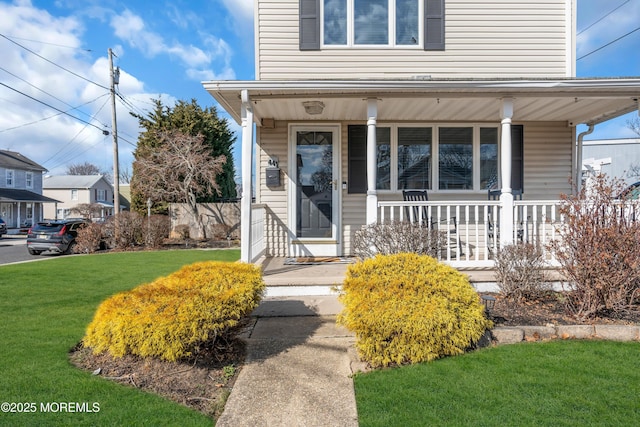 property entrance with a yard and covered porch