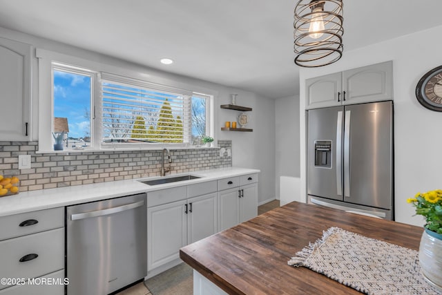 kitchen with sink, appliances with stainless steel finishes, backsplash, hanging light fixtures, and wood counters