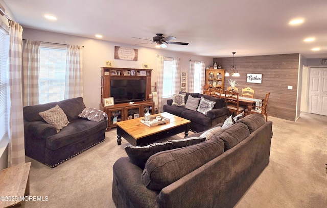 living room featuring ceiling fan, light colored carpet, and wooden walls