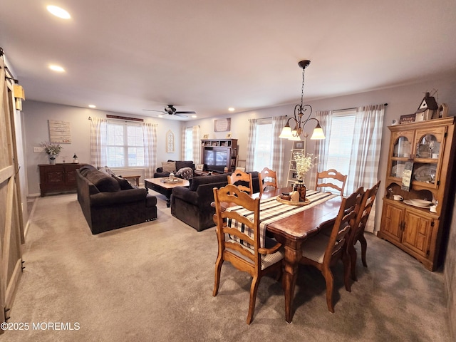 carpeted dining room featuring ceiling fan with notable chandelier and a wealth of natural light