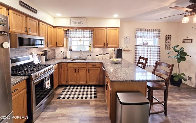 kitchen featuring stainless steel appliances, sink, a breakfast bar area, and stone counters