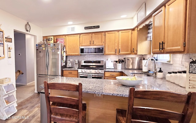 kitchen with sink, light stone counters, tasteful backsplash, kitchen peninsula, and stainless steel appliances