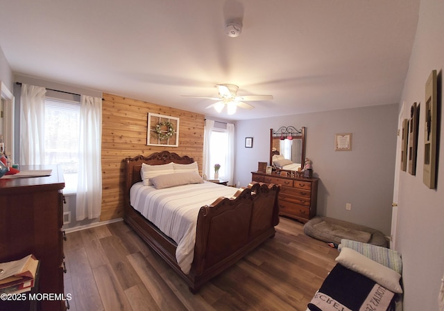 bedroom featuring ceiling fan, dark wood-type flooring, and wooden walls