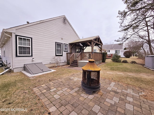 back of property with a yard, a fire pit, and a gazebo