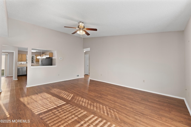 unfurnished living room featuring ceiling fan with notable chandelier, vaulted ceiling, hardwood / wood-style floors, and a textured ceiling