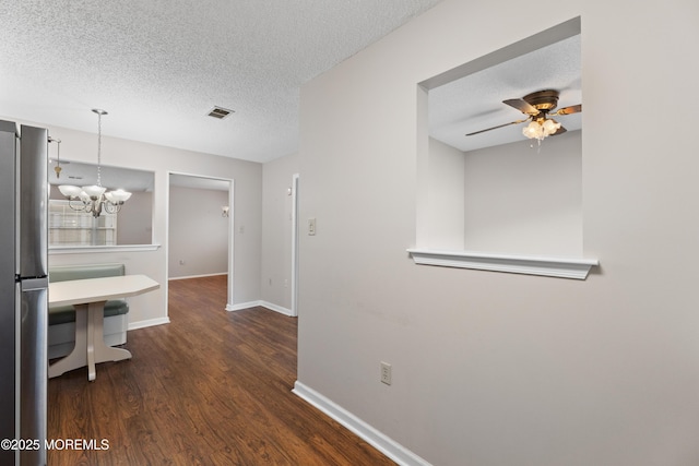 hall featuring dark wood-type flooring, a chandelier, and a textured ceiling