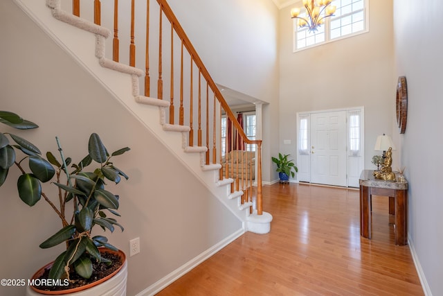 entrance foyer featuring an inviting chandelier, hardwood / wood-style floors, and a towering ceiling