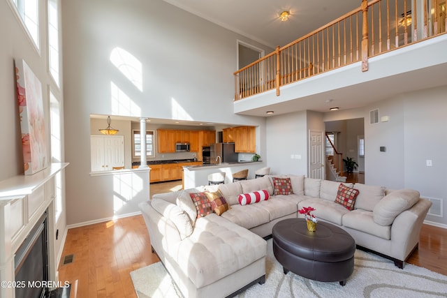 living room featuring a towering ceiling, a fireplace, and light hardwood / wood-style flooring