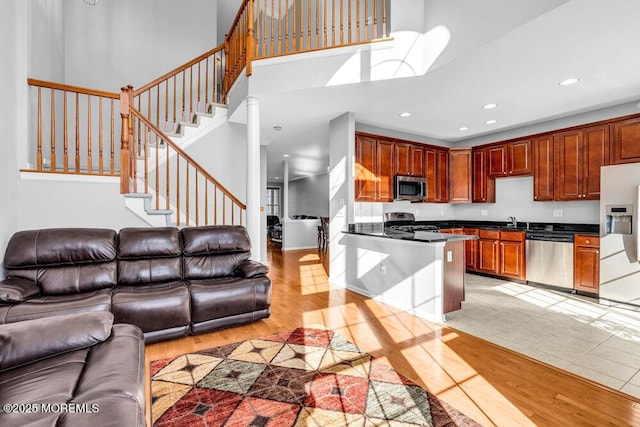 kitchen featuring stainless steel appliances, sink, a high ceiling, and light wood-type flooring