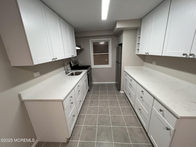 kitchen featuring sink, light tile patterned floors, white cabinets, and black fridge