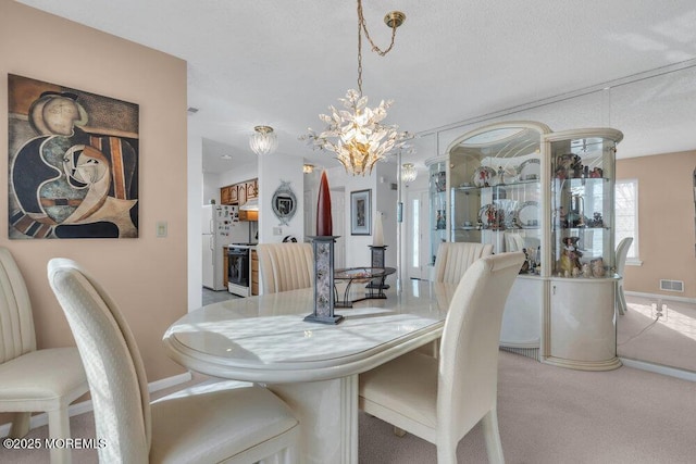 dining room featuring light carpet and a chandelier