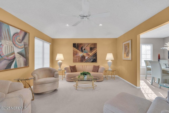 living room with ceiling fan, light carpet, and a textured ceiling