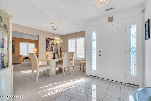 tiled foyer with an inviting chandelier and a textured ceiling