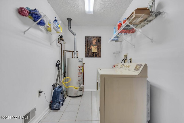 clothes washing area with gas water heater, light tile patterned floors, a textured ceiling, and independent washer and dryer