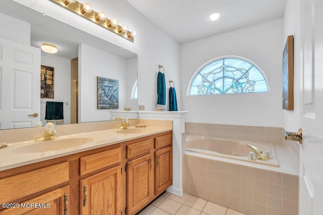 bathroom featuring tile patterned flooring, vanity, tiled bath, and a textured ceiling