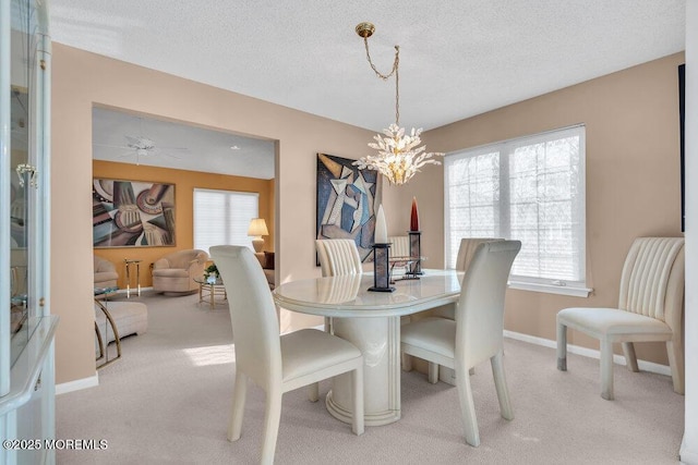 carpeted dining space featuring ceiling fan with notable chandelier and a textured ceiling